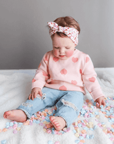 Baby girl is wearing a heart print headwrap for little girls from By Bella Boutique.